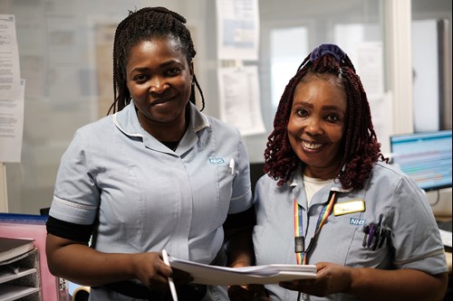 Two black, female nurses smiling at the camera.
