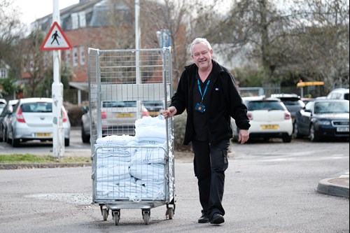 Male staff member pushing trolley outside.