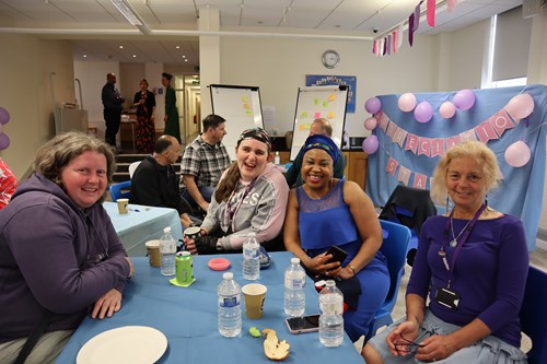 A group of four women smiling while they sit at a table at a party