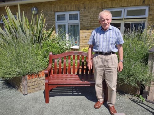 Photo of Peter Watson standing in front of a bench in the Clifton Lodge garden