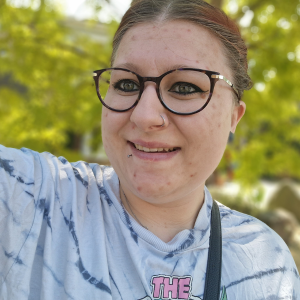 Woman with hair tied back, wearing glasses smiling