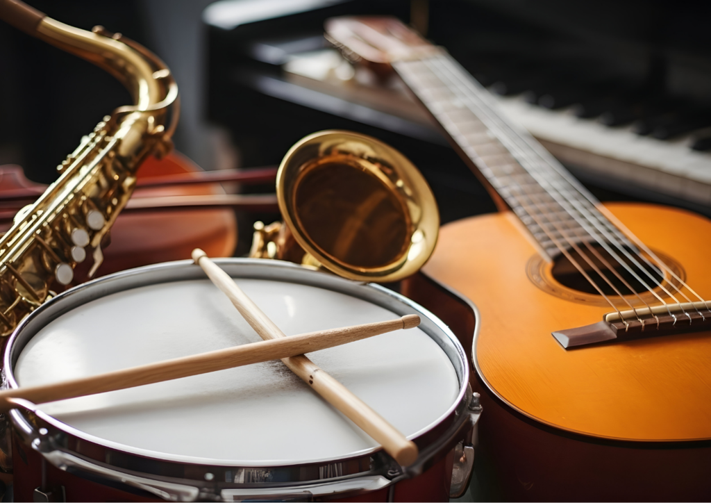 Close-up collection of musical instruments, including a snare drum with crossed drumsticks, an acoustic guitar, a saxophone, a violin, and a piano keyboard in the background.