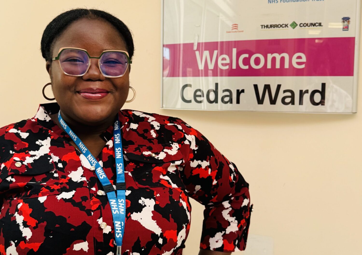 woman standing next a sign saying 'Welcome to Cedar Ward'