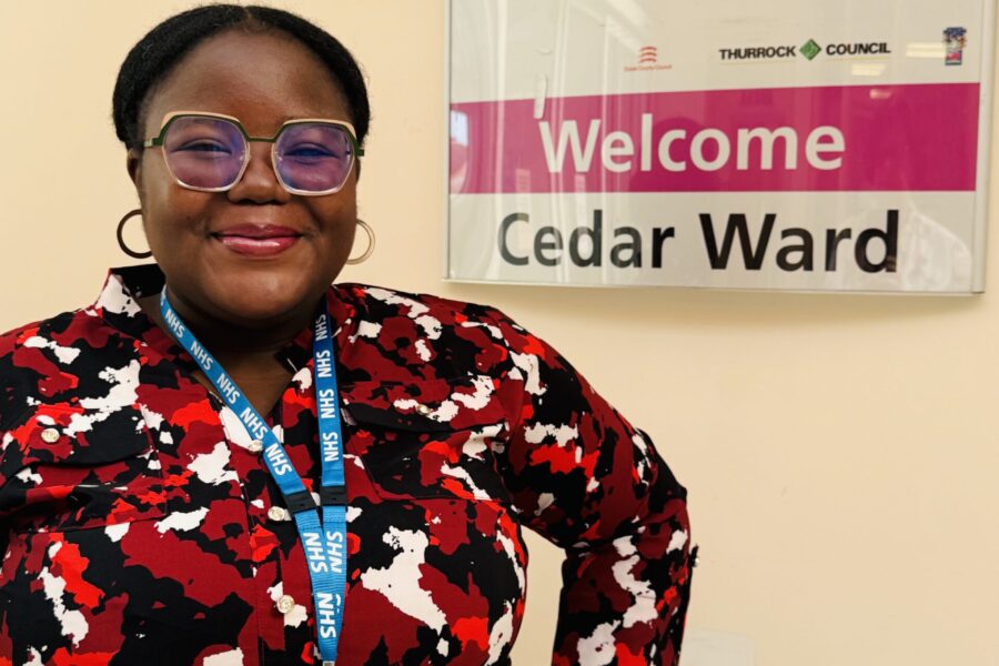 woman standing next a sign saying 'Welcome to Cedar Ward'