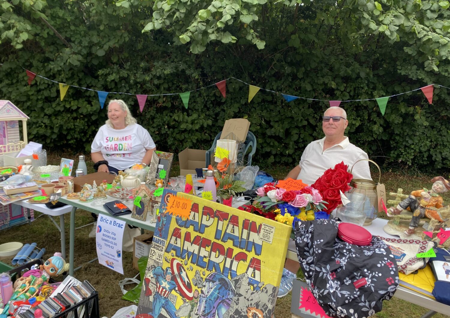 A man and a woman sat at a tombola stand.