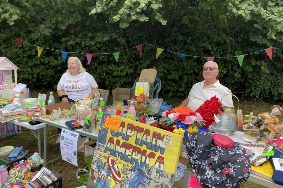A man and a woman sat at a tombola stand.
