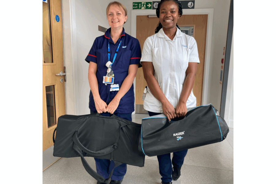 Two women in clinical uniforms holding duffel bags.