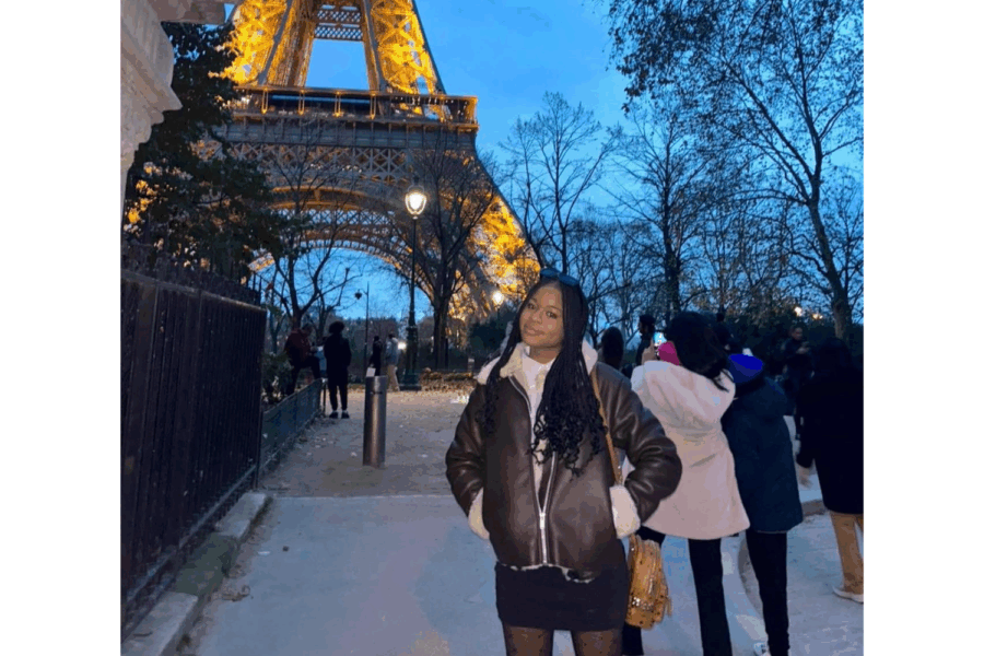 Photograph of April Longe standing in from of the Eiffel Tower.