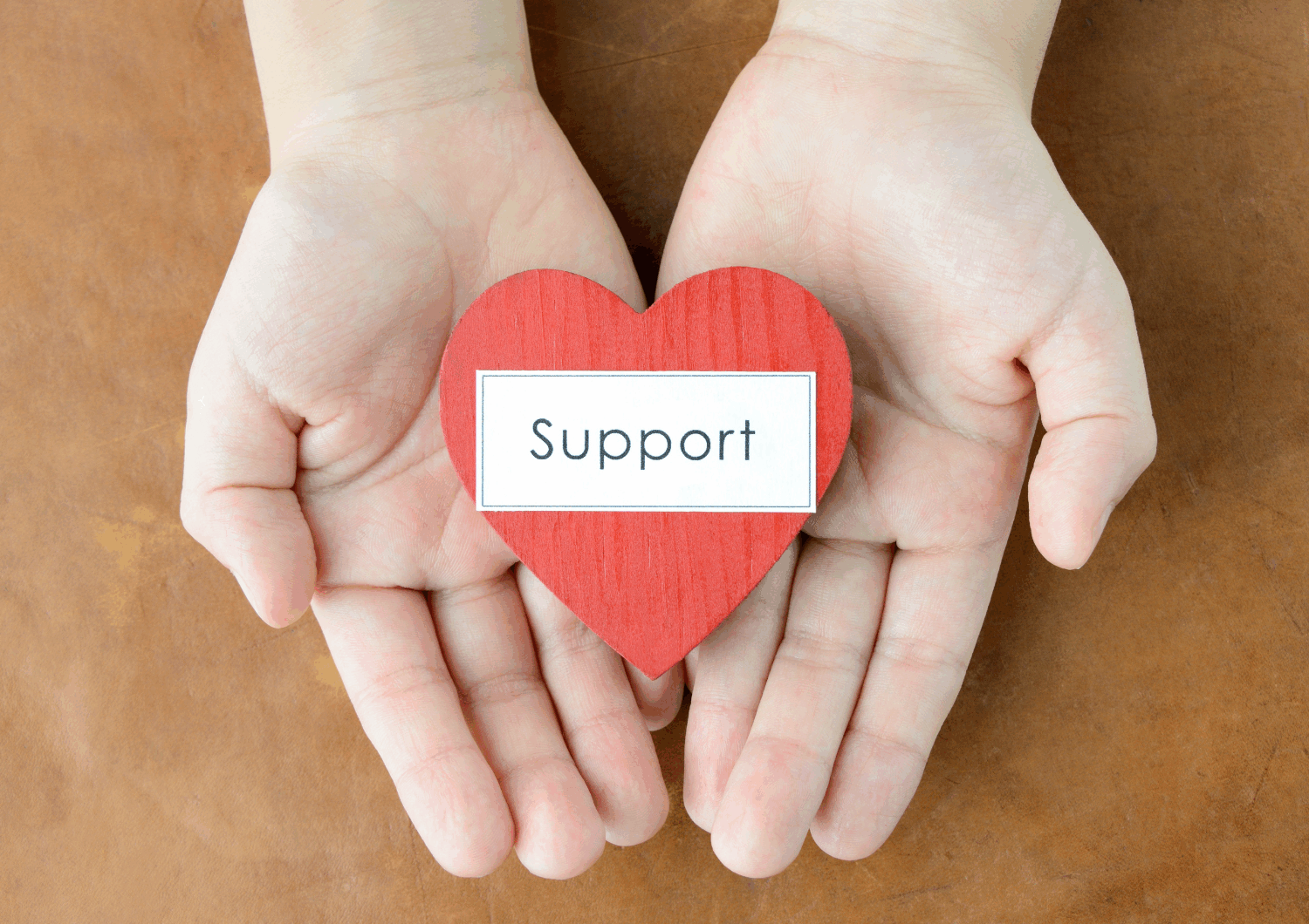 Picture pf hands holding a cut out shaped like a heart with the words 'support' on it.