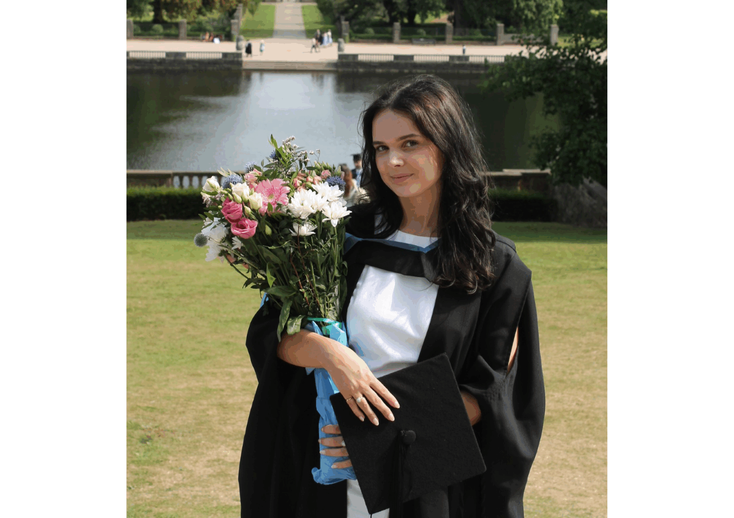 Photograph of Louisa in her graduation gown, holding a bouquet of flowers.