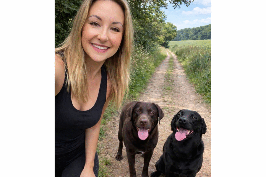 Photograph of Hannah smiling at the camera, with her two dogs.