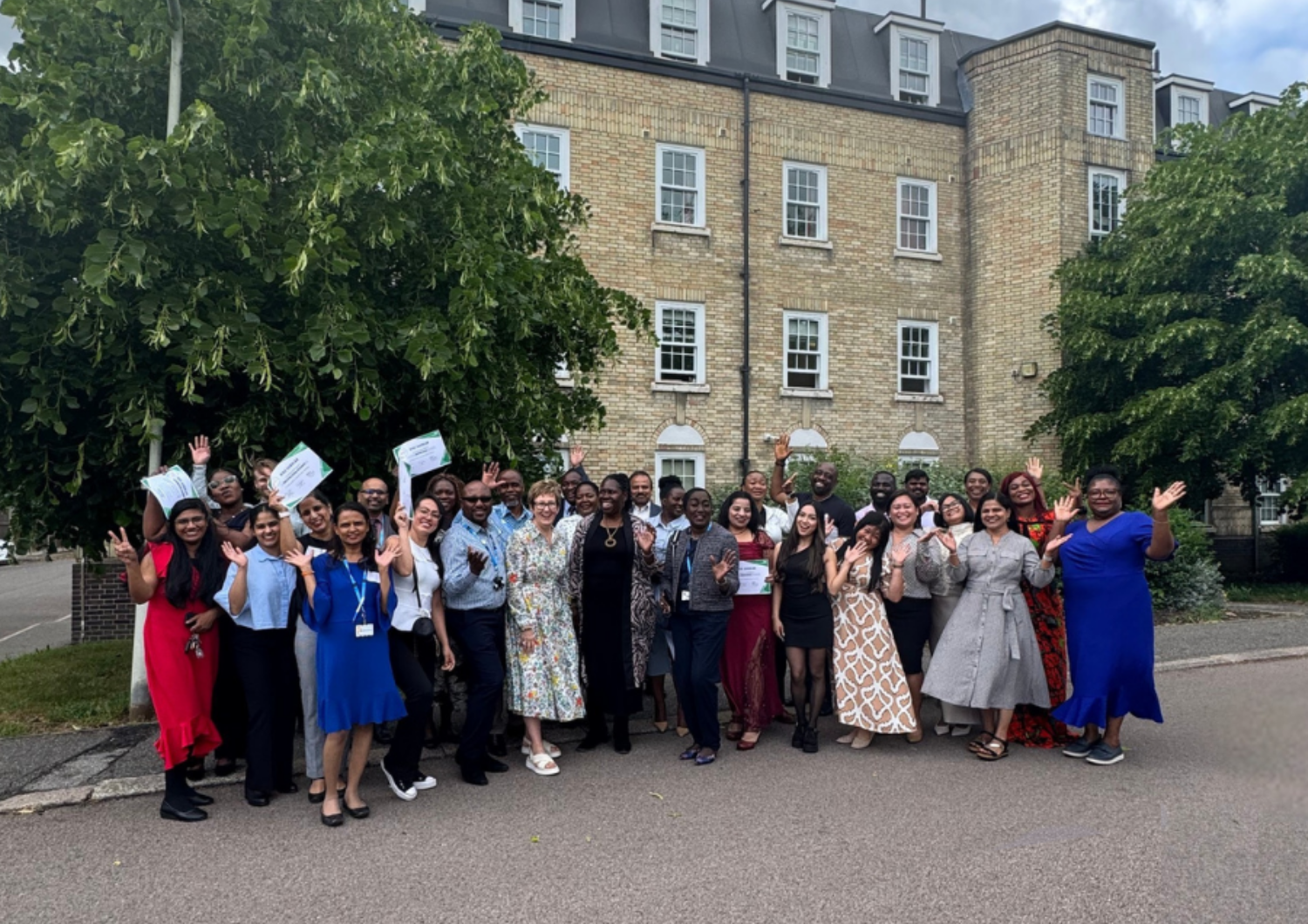 Group of people standing in front of a building and trees.
