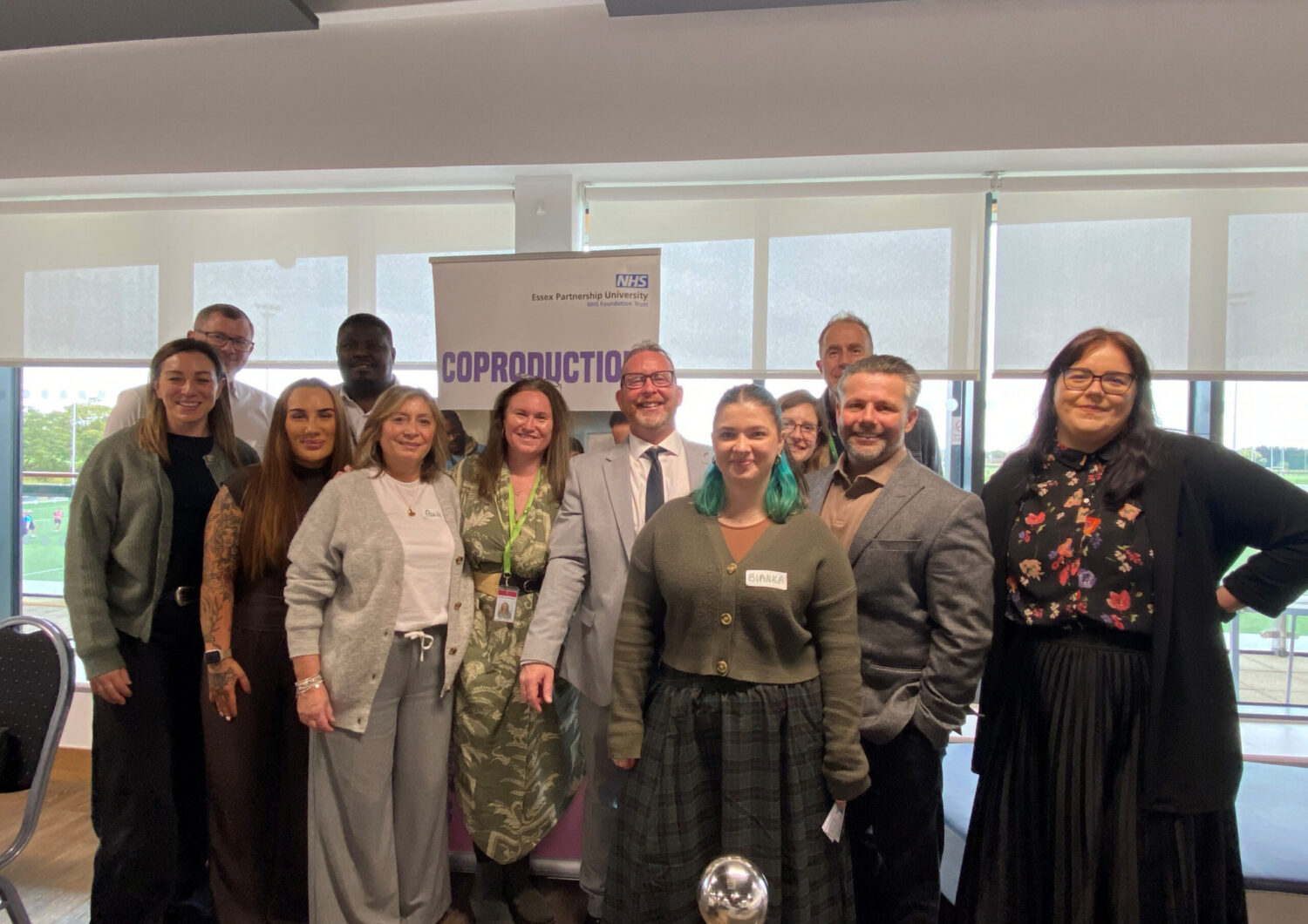A group photo of eleven attendees standing together in front of a banner that reads 