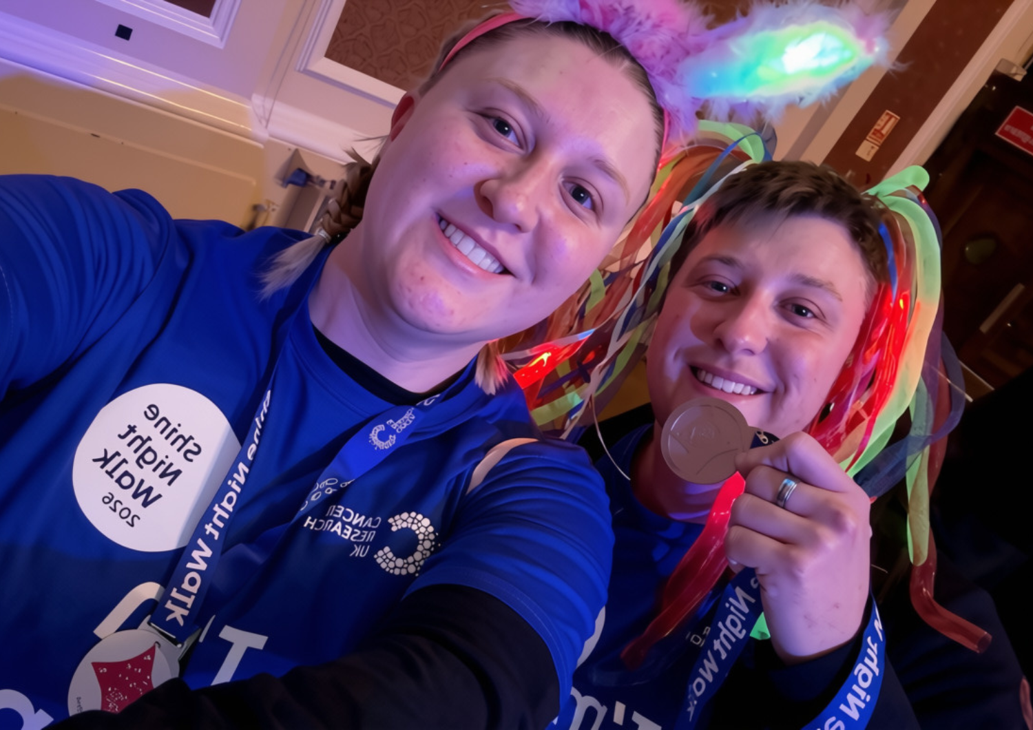 Two smiling women take a selfie wearing matching blue Cancer Research UK 
