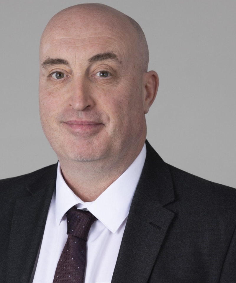 Photo of Andrew McMenemy wearing a blue suit jacket, blue tie and a white shirt