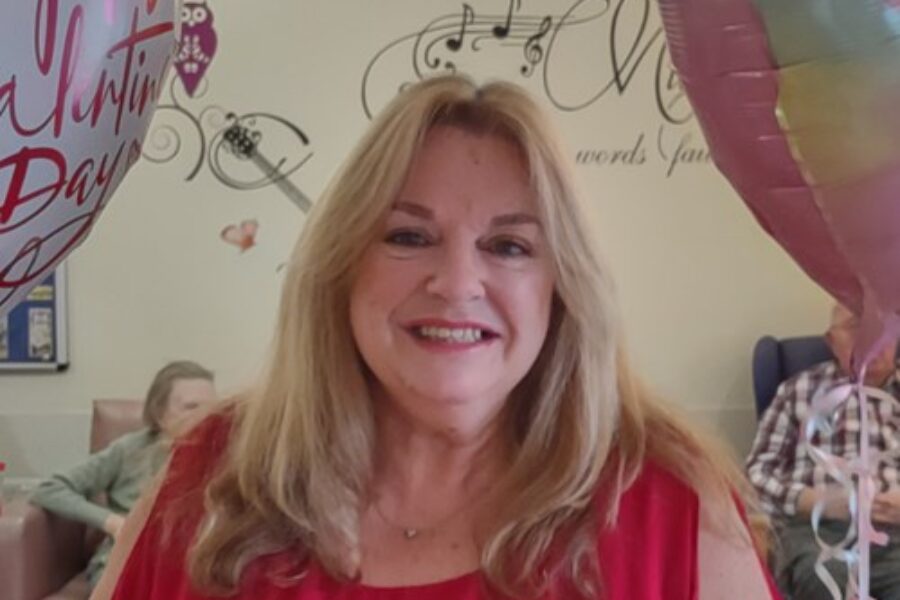 Sue wearing a red top smiling at the camera