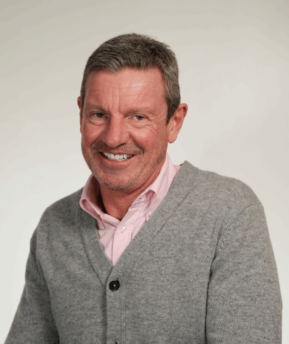 Photo of Trevor Smith wearing a grey cardigan and a pink shirt