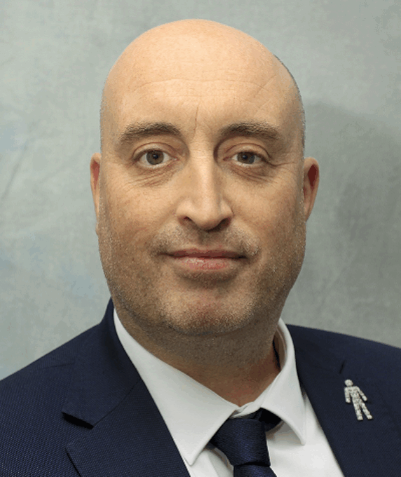 Photo of Andrew McMenemy wearing a blue suit jacket, blue tie and a white shirt