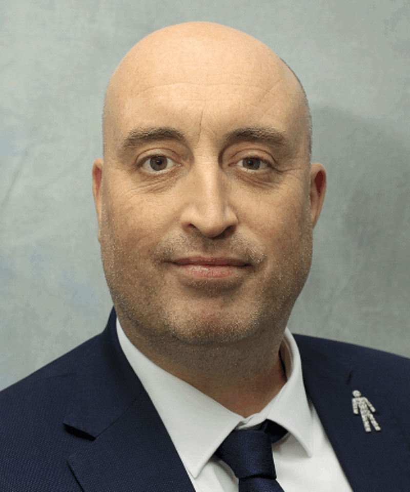 Photo of Andrew McMenemy wearing a blue suit jacket, blue tie and a white shirt