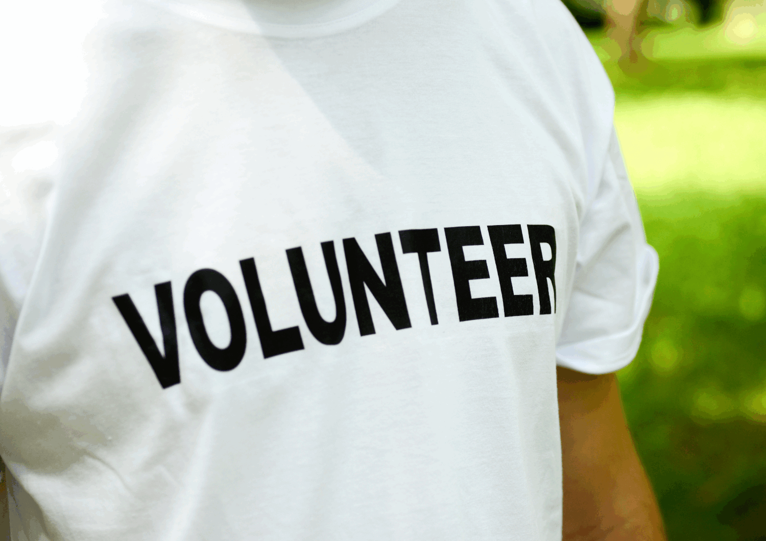 White t-shirt with the text volunteer written in black.