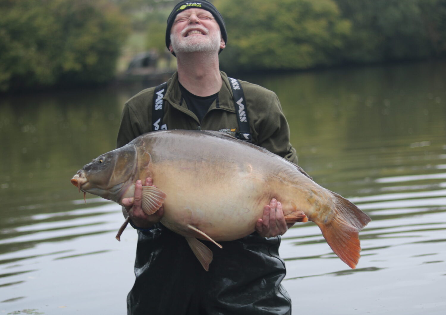 iCARP member in the middle of a lake holding a large fish.