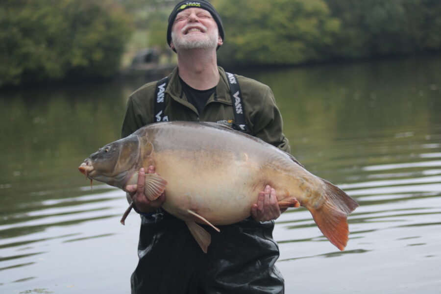 iCARP member in the middle of a lake holding a large fish.
