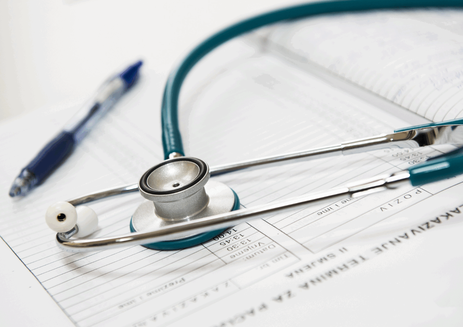 Photo with a stethoscope and pen on top of an appointment book.